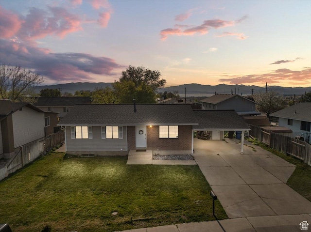 view of front of house with concrete driveway, a mountain view, a carport, and a yard