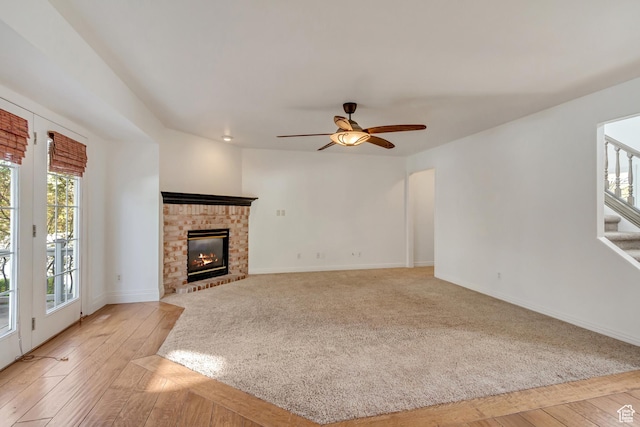 unfurnished living room with light wood-type flooring, stairs, a ceiling fan, and baseboards