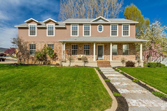 view of front of house featuring a front lawn, brick siding, and a porch