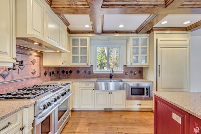 kitchen with light wood-type flooring, built in appliances, a sink, and coffered ceiling