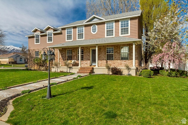 view of front of home with brick siding, a porch, and a front lawn