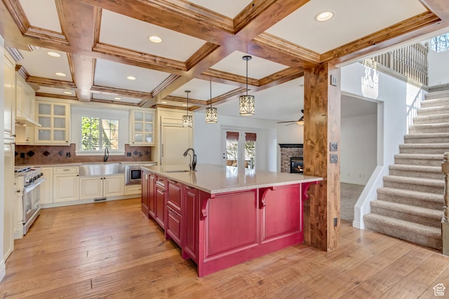kitchen featuring a warm lit fireplace, stainless steel range, a ceiling fan, and a sink