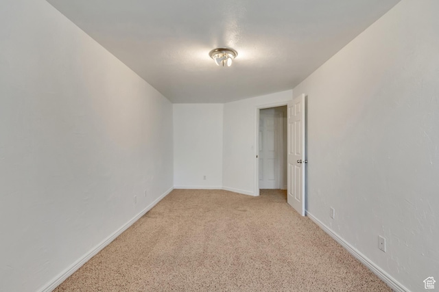 unfurnished room with light carpet and baseboards
