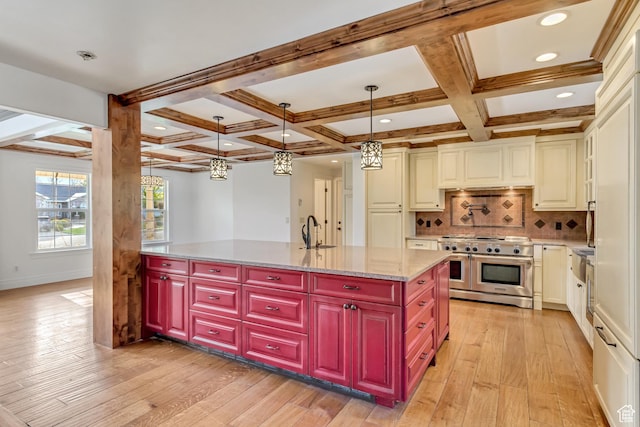 kitchen with light wood finished floors, a sink, coffered ceiling, and range with two ovens