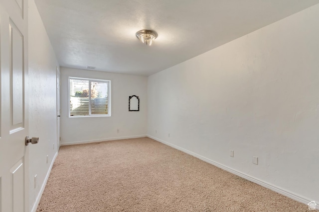 spare room with baseboards and light carpet