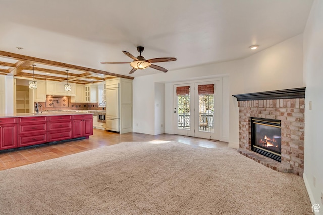 unfurnished living room with coffered ceiling, light carpet, beam ceiling, a brick fireplace, and ceiling fan