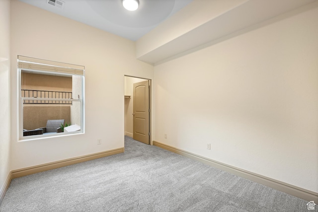 unfurnished bedroom featuring a closet, a spacious closet, carpet floors, baseboards, and visible vents