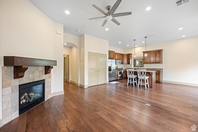 living room featuring visible vents, arched walkways, ceiling fan, and dark wood finished floors