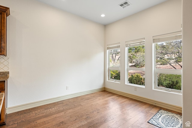 empty room featuring recessed lighting, hardwood / wood-style floors, visible vents, and baseboards