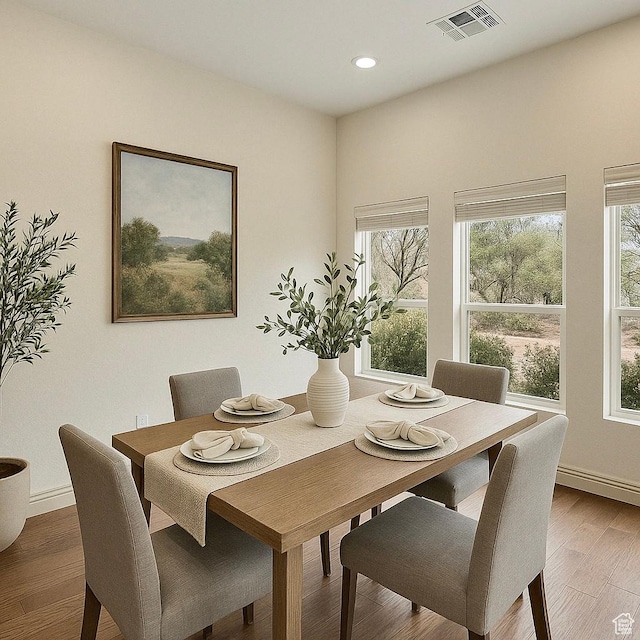 dining room featuring a healthy amount of sunlight, wood finished floors, visible vents, and recessed lighting