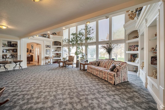 living room featuring arched walkways, built in features, a textured ceiling, and carpet floors