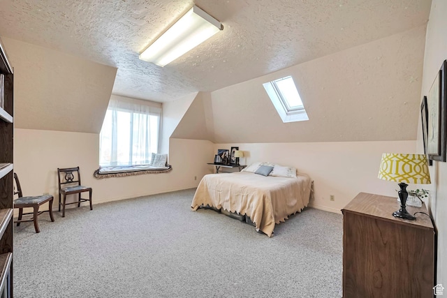 carpeted bedroom featuring vaulted ceiling with skylight, a textured ceiling, and baseboards