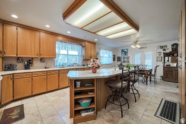 kitchen with a ceiling fan, a kitchen breakfast bar, a center island, and a healthy amount of sunlight