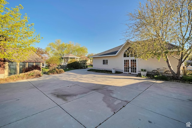 rear view of house featuring french doors, a patio, and stucco siding