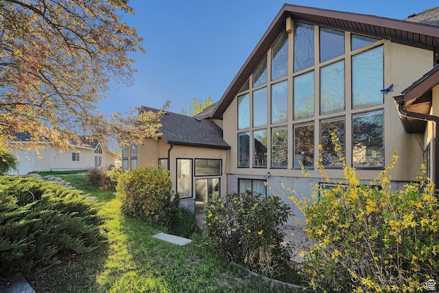 rear view of property featuring stucco siding and a shingled roof