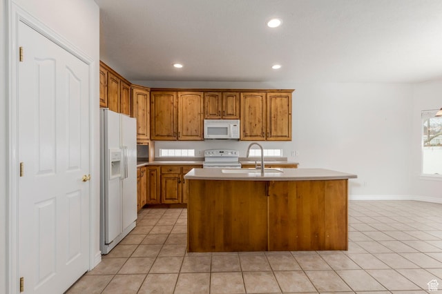 kitchen with light countertops, light tile patterned floors, a sink, white appliances, and a center island with sink