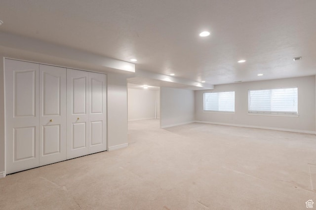below grade area featuring visible vents, light carpet, baseboards, and recessed lighting