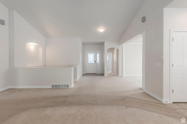 interior space featuring arched walkways, vaulted ceiling, visible vents, and carpet flooring