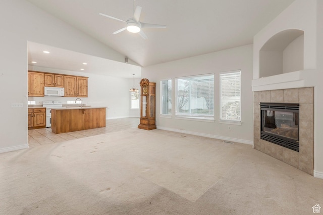 unfurnished living room with vaulted ceiling, a tile fireplace, light colored carpet, and ceiling fan