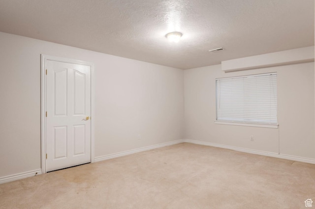 spare room with carpet floors, baseboards, and a textured ceiling