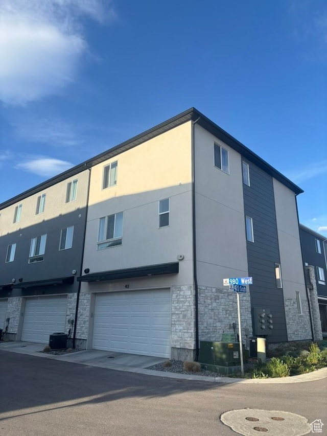 413 S 980 W, American Fork, UT 84003 - back of house featuring stucco siding, stone siding, cooling unit, and a garage
