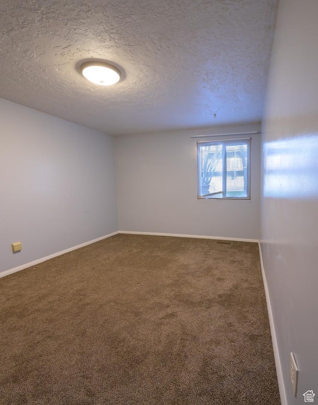 unfurnished room with carpet floors, a textured ceiling, and baseboards