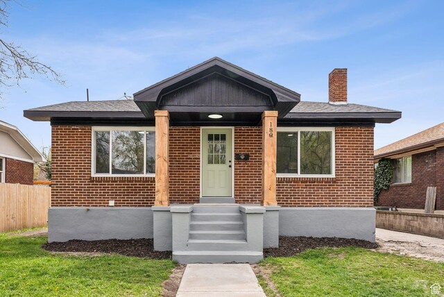 bungalow with brick siding, fence, and a chimney