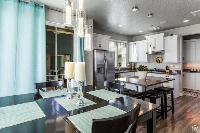 kitchen with dark countertops, pendant lighting, a textured ceiling, appliances with stainless steel finishes, and white cabinetry