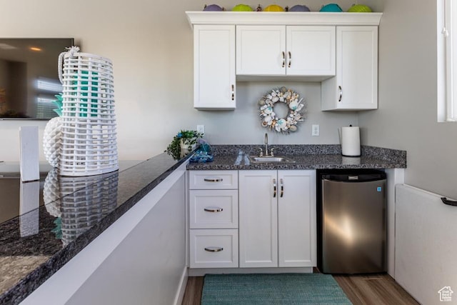 bar with indoor wet bar, a sink, refrigerator, and dark wood finished floors