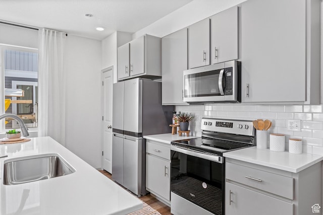 947 N Riverside Dr Unit 977, Saratoga Springs, UT 84045 - kitchen featuring light countertops, a sink, decorative backsplash, gray cabinetry, and appliances with stainless steel finishes
