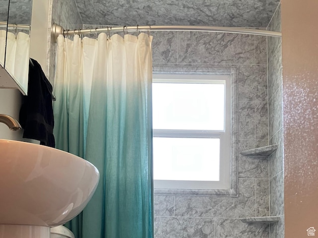 full bathroom featuring a wealth of natural light, a sink, and curtained shower