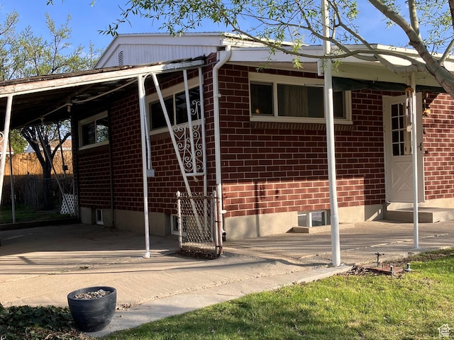 exterior space with brick siding, a carport, and fence
