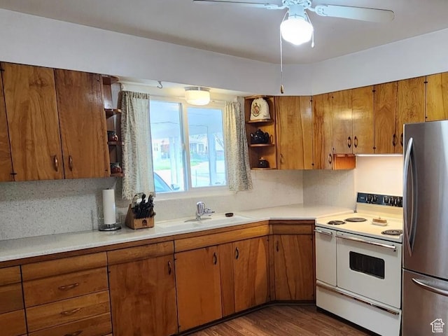 kitchen featuring brown cabinets, light countertops, a sink, white range with electric cooktop, and freestanding refrigerator