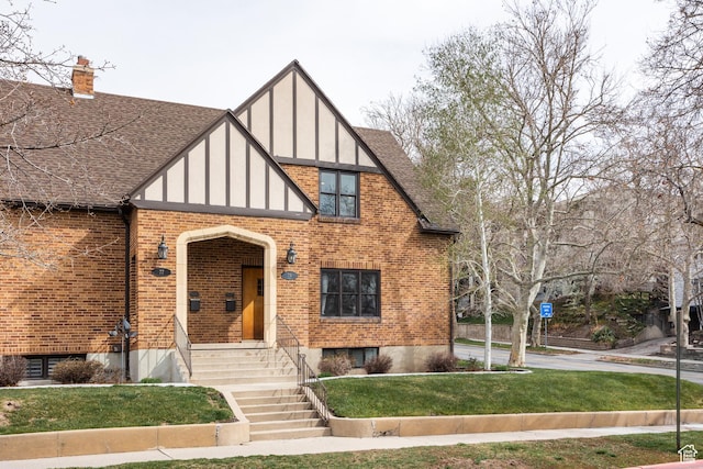 79 E Hillside Ave, Salt Lake City, UT 84103 - english style home with a chimney, board and batten siding, a front yard, brick siding, and roof with shingles