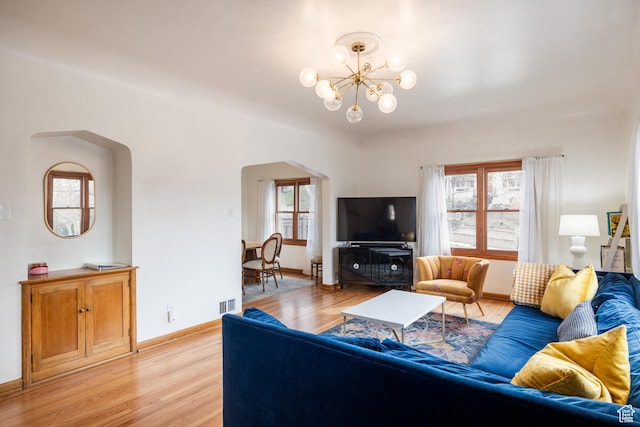 79 E Hillside Ave, Salt Lake City, UT 84103 - living area with light wood-style flooring, arched walkways, visible vents, an inviting chandelier, and baseboards
