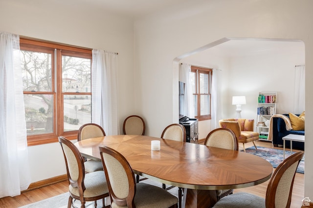 79 E Hillside Ave, Salt Lake City, UT 84103 - dining area with light wood-style flooring, baseboards, arched walkways, and a healthy amount of sunlight
