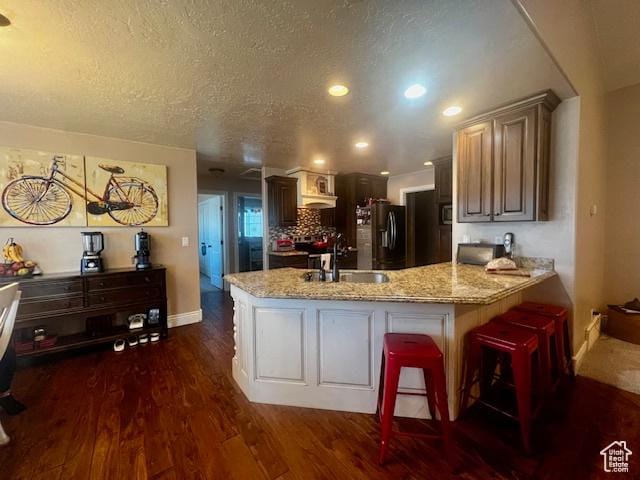 164 Park Ridge Dr, Roosevelt, UT 84066 - kitchen with light stone counters, a sink, baseboards, a peninsula, and refrigerator with ice dispenser
