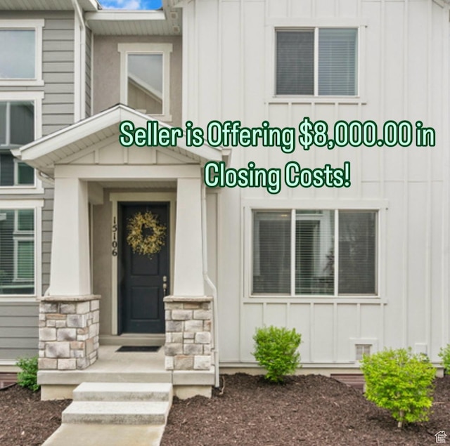 doorway to property with board and batten siding and stone siding
