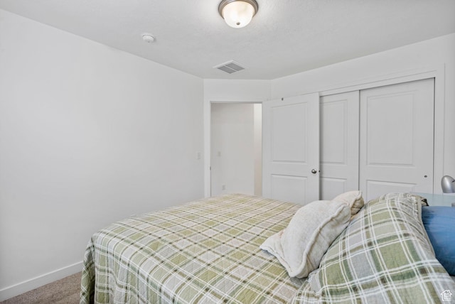 bedroom with carpet floors, baseboards, visible vents, and a closet