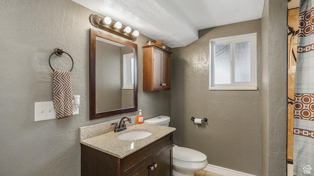 bathroom with a textured wall, toilet, and vanity