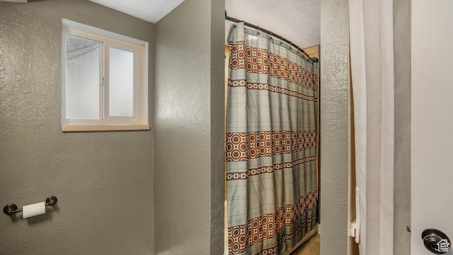 full bath with a textured wall and curtained shower
