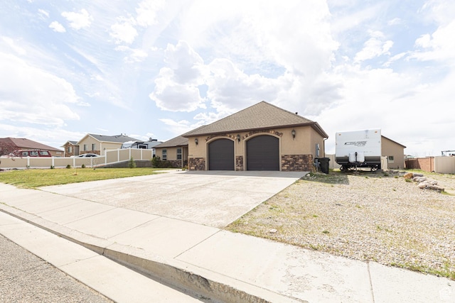 5095 N Ridgeview Cir, Enoch, UT 84721 - view of front of property featuring driveway, stone siding, fence, a garage, and stucco siding