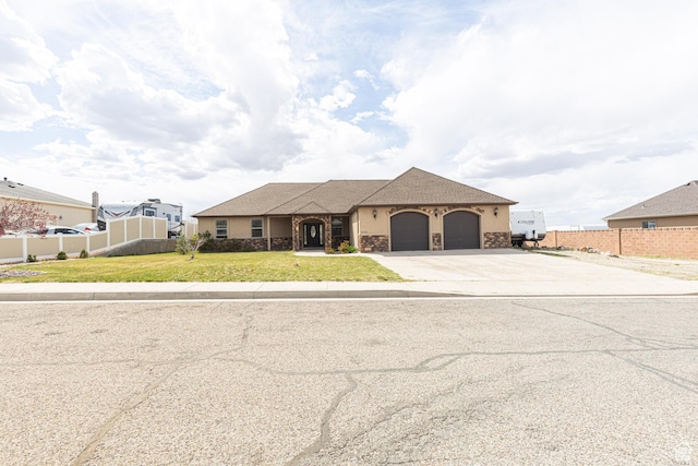 5095 N Ridgeview Cir, Enoch, UT 84721 - view of front of property with concrete driveway, a front lawn, stone siding, fence, and a garage