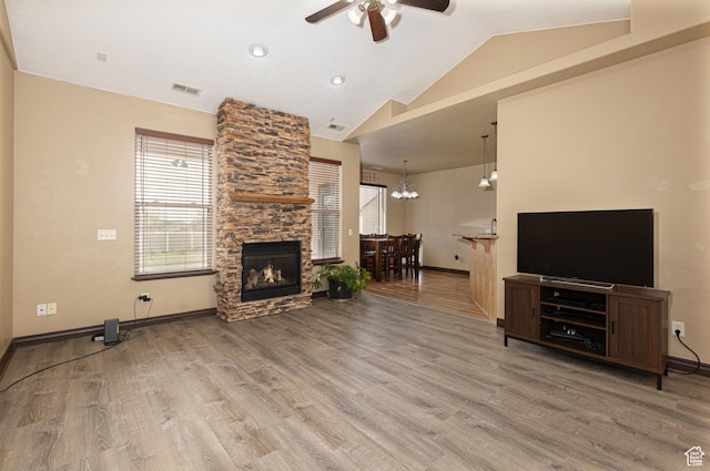 5095 N Ridgeview Cir, Enoch, UT 84721 - living area with vaulted ceiling, a stone fireplace, wood finished floors, baseboards, and ceiling fan with notable chandelier