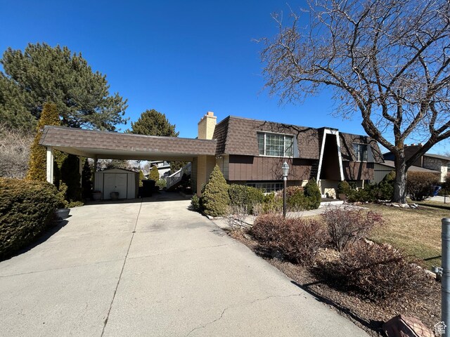 3748 W 5140 S, Taylorsville, UT 84129 - view of front of property with a chimney, driveway, a shingled roof, an outbuilding, and a storage unit