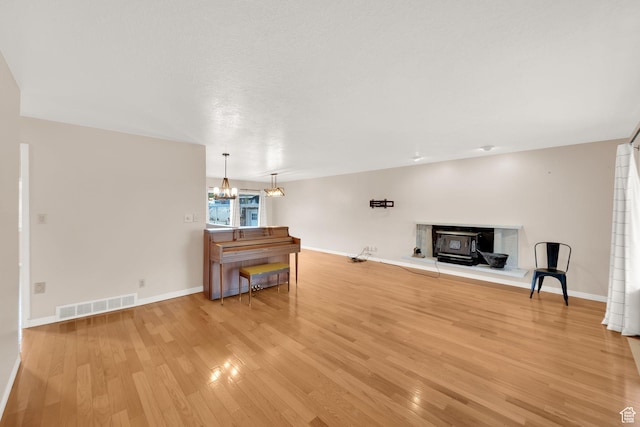 unfurnished living room with a chandelier, baseboards, visible vents, and light wood-style floors