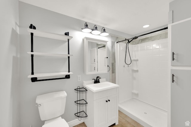 bathroom with baseboards, vanity, toilet, and tiled shower