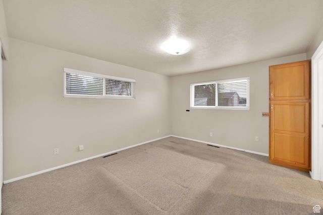 spare room with plenty of natural light, visible vents, baseboards, and light colored carpet