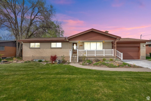 ranch-style house with brick siding, a yard, an attached garage, and a porch