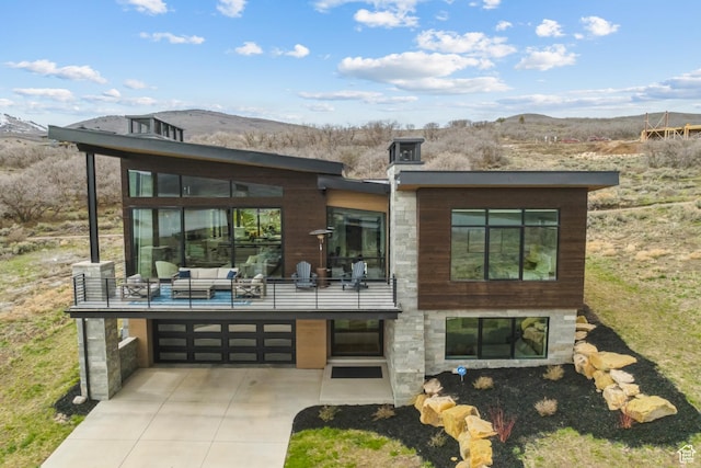 11431 N Ursa Cir Unit 56, Heber City, UT 84032 - rear view of property featuring concrete driveway, stone siding, an attached garage, a mountain view, and an outdoor hangout area